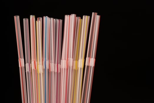 Assortment of multicoloured plastic drinking straws isolated on black