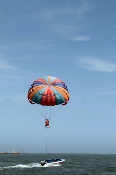 One man is parasailing over the clean sea.