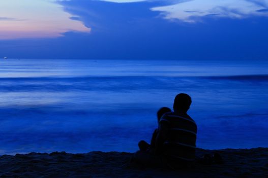 A father and son enjoying sunset at a tropical beach