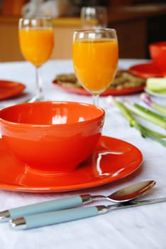 red plates and orange juice served on table in kitchen