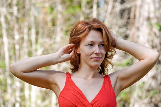 Portrait of red-haired adult woman in nature