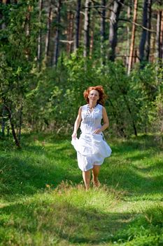 Red-haired woman running on path in the wood