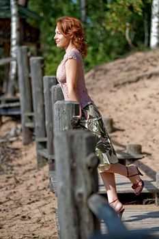 Red-haired adult woman in dune looking at the sea