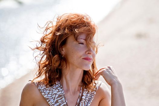 Portrait of red-haired adult women in dune at the sea