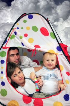 Happy young family with the son in a small house on a background of clouds