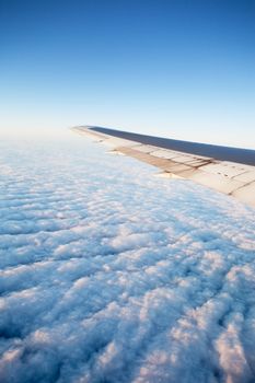 A wing of an airplane flying of a cloudscape