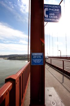 A suicide emergency phone on the San Francisco Bridge with the sun signifying hope