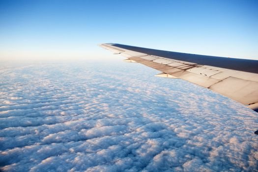 A wing of an airplane flying of a cloudscape