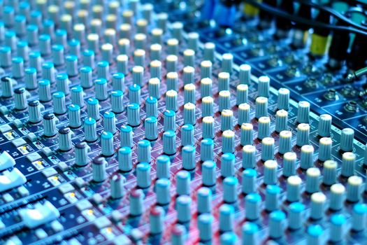 soundboard mixing desk under blue stage lighting