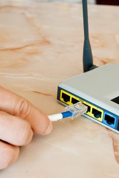 A hand pluging an ethernet cable into ab old a router