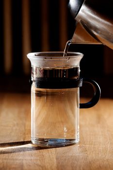 Early morning tea - glass being filled with water with strong directional  morning light