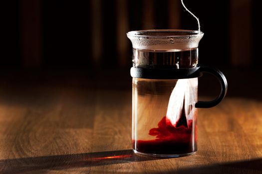 A tea bag in a cup of hot water with strong directional morning light