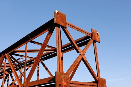 Fragment of rusty metal pillar against background of blue sky