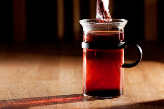 A tea bag in a cup of hot water with strong directional morning light