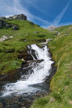 fresh waters are flowing with a small cascade under a blue sky. Photo taken with polarized filter