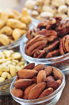 Almonds, cashews pistachio and pine nuts in glass bowls