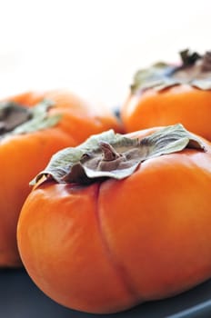 Orange whole ripe persimmon fruit on a plate