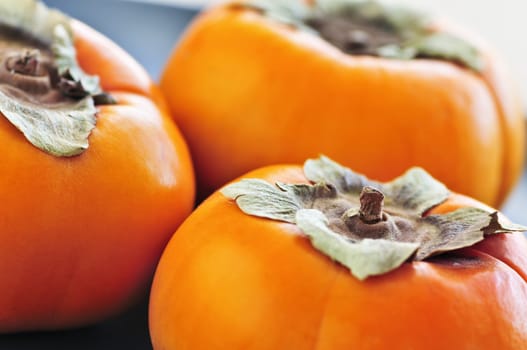 Orange whole ripe persimmon fruit on a plate