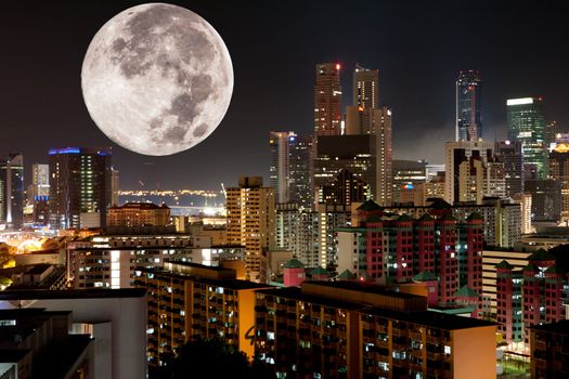 A very large moon rising over a metropolis