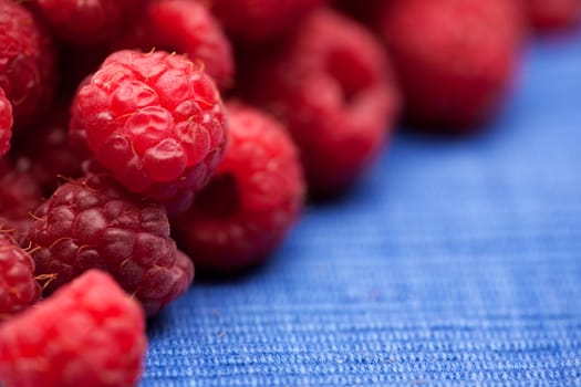 Fresh raspberries isolated on a blue cloth.  Shallow depth of field.