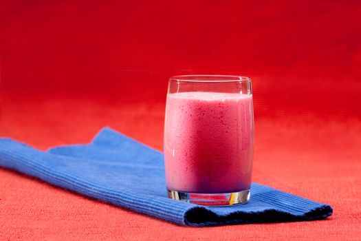 A red berry smoothie isolated on blue and red