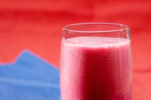 A red berry smoothie isolated on blue and red