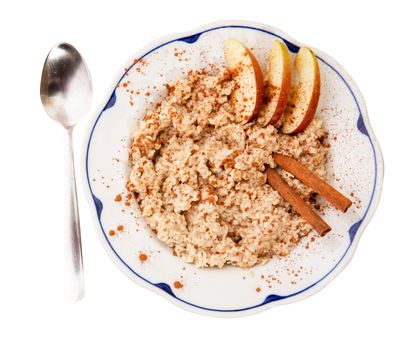 A bowl of porridge with apple and cinnamon spices isolated on white