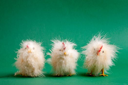 Three funny little easter decorations lined up on a green background