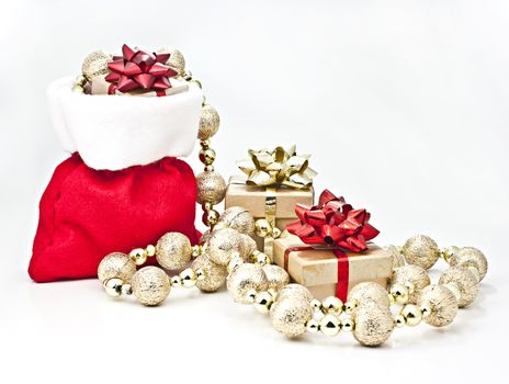 On a white background Christmas gift bag with gifts and golden ball strings.
