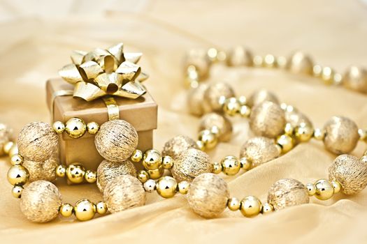 The gold background gold gift box with a string of Christmas ornamental ball.

