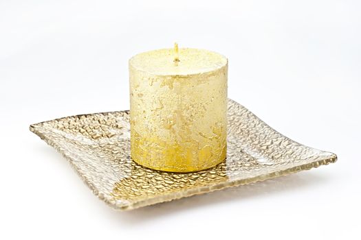 Isolated on white background gold candle in a glass dish.

