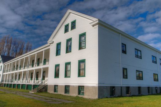 White barracks at Fort Worden with green lined windows against a blue sky with clouds