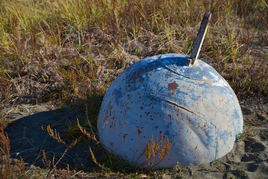 Old blue steel Land locked Steel Bouy stuck in the sand