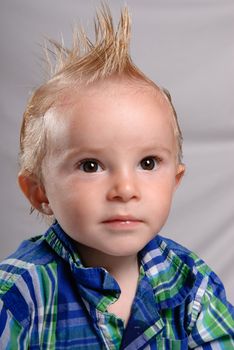 A closeup portrait of a spiky haired boy toddler wearing a nice shirt