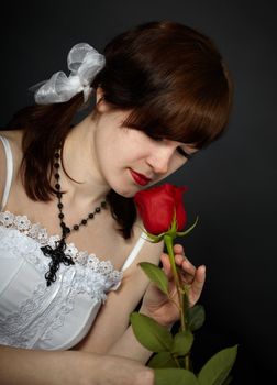 The young beautiful girl smells a red rose