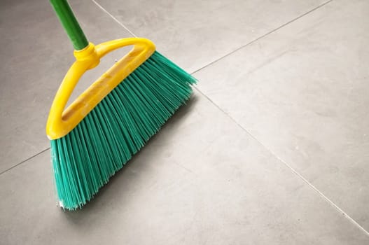 Green plastic broom during a home cleaning