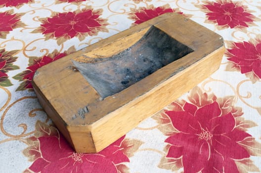 Wooden ashtray over a red flowered table cloth