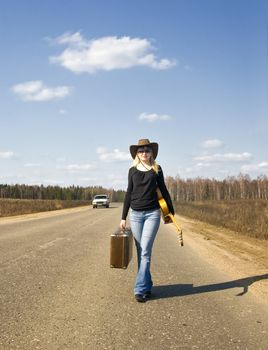 country girl with guitar goes on road solitary under sky