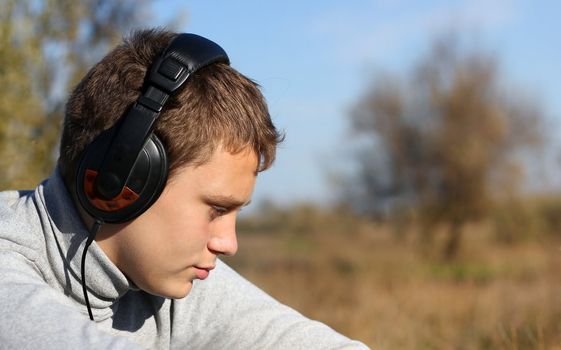 Boy Enjoying Music in headphones in autumn day