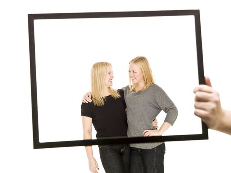 Two blond girls in a frame isolated on white background