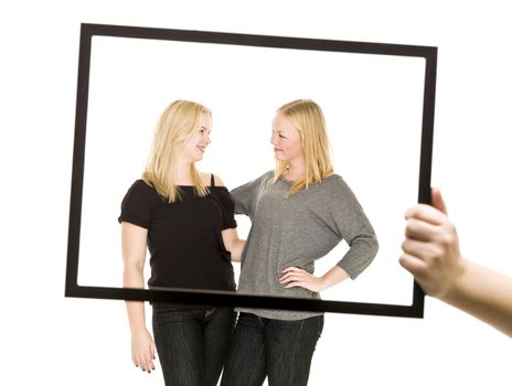 Two blond girls in a frame isolated on white background
