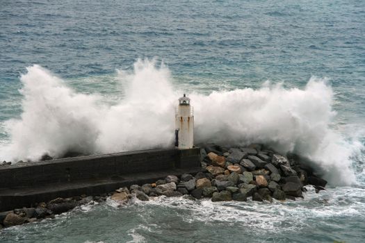 waves break on the lighthouse at Camogli, Italy