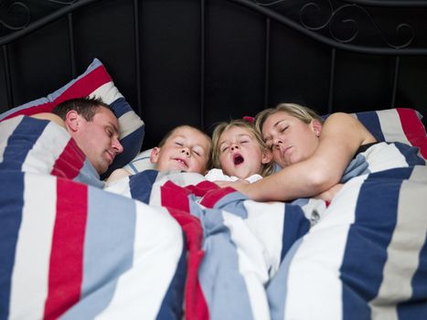 Family sleeping in the same bed