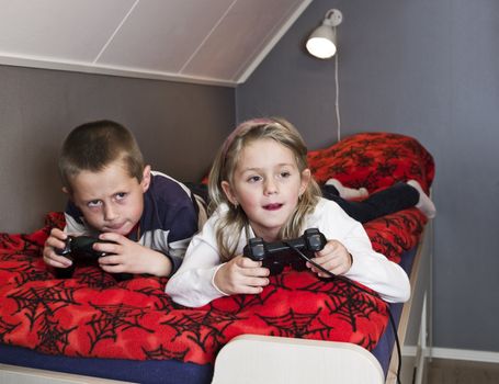 Siblings playing Video Games lieing in the bed