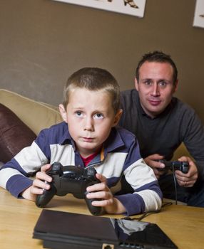 Father and son Playing Video Games sitting in the sofa