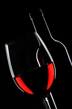 Red wine bottle and glass silhouette over black background