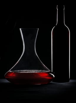 Red wine, bottle and decanter silhouette over black background