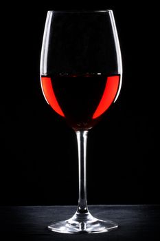 Red wine glass silhouette over black background