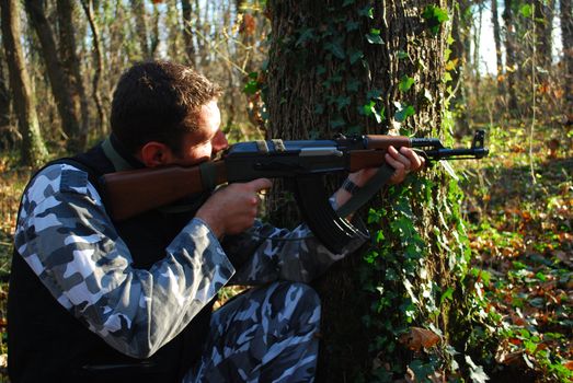 Soldier in camouflage aiming with his rifle outdoor