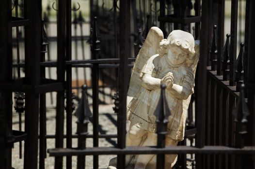 Amgel in a cemetary behind wrought iron bars